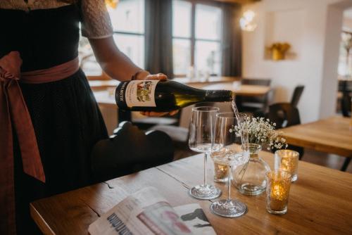 a woman pouring wine into glasses on a table at Hotel Alpin Tyrol - Kitzbüheler Alpen in Sankt Johann in Tirol