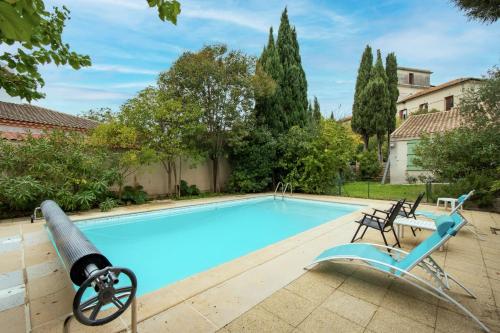 einen Pool mit zwei Stühlen neben einem Haus in der Unterkunft Maison Calme et Sérénité - Welkeys in Montpellier