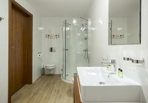 a white bathroom with a sink and a shower at Hotel Logos in Zakopane