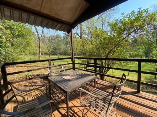 a table and chairs on a porch with a view of a field at Buhleni Farm Chalets in Ezulwini