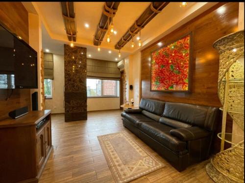 a living room with a leather couch and a painting at Дельмар Миронова Европейская 9 А in Dnipro