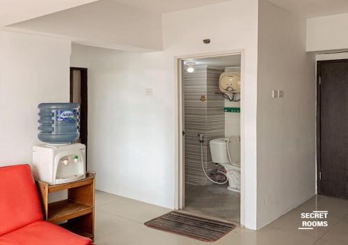 baño con aseo y silla roja en The Jarrdin Apartement by Secret Rooms, en Bandung