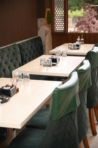 a row of tables in a restaurant with green chairs at Lemon wood suites in Pune
