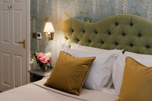 a bedroom with a bed with a green headboard and pillows at The Milbank Arms in Richmond