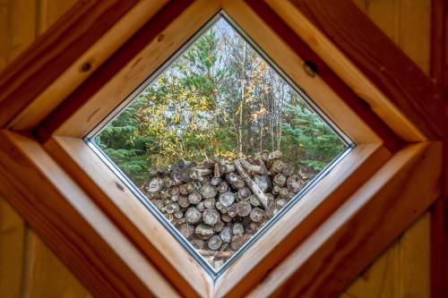 a window in a cabin with a pile of logs at Cozy And Spacious Holiday Home Near Torup Strand Close To The North Sea in Fjerritslev