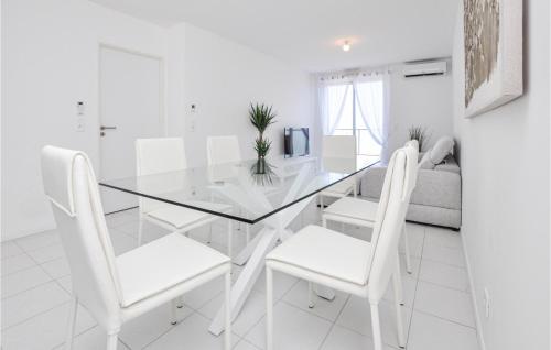 une salle à manger blanche avec une table en verre et des chaises blanches dans l'établissement 2 Bedroom Cozy Apartment In La Turbie, à La Turbie