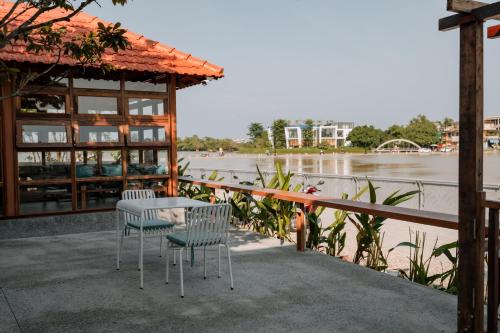 a patio with a table and chairs next to a river at Hue River Side Villa in Hue