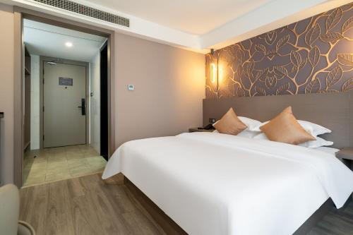 a bedroom with a large white bed and a wall at Ruilan Grandyard Hotel in Nanjing