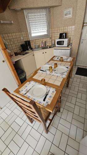 une cuisine avec une table avec des assiettes dessus dans l'établissement Maison 30m2 Wifi 9mn à Pied Plage Présidents Draps fournis pour le lit, à Les Sables-dʼOlonne
