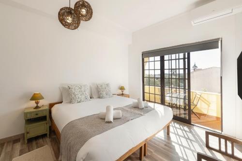 a white bedroom with a large bed and a window at Casa do Convento in Óbidos