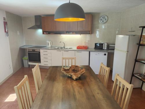 a kitchen with a wooden table with chairs and a kitchen with a refrigerator at Quinta da Barroquinha in Vale de Prazeres