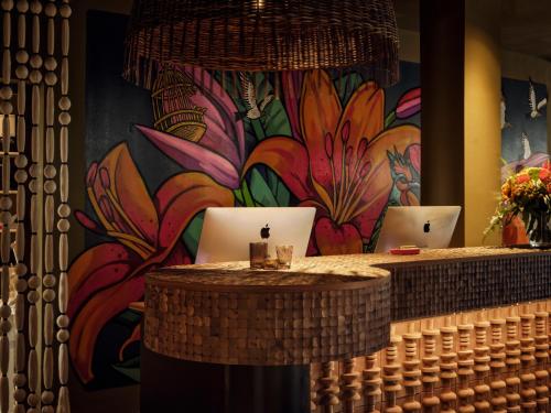 a colorful mural of flowers on a wall with two laptops at Bikini Island & Mountain Hotel Es Trenc -Adults only- in Colonia Sant Jordi