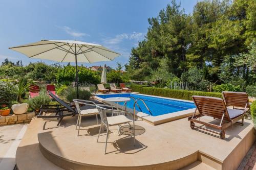 a patio with chairs and an umbrella next to a pool at House Sanda in Mirce