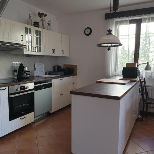 a kitchen with white cabinets and a black counter top at Pottos Porta in Váncsod