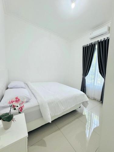 a white bedroom with a bed and a table at The Villas in Bogor