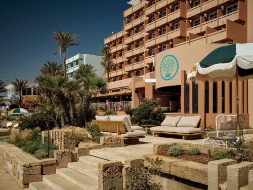 a resort with couches and chairs in front of a building at Bikini Island & Mountain Hotel Es Trenc -Adults only- in Colonia Sant Jordi