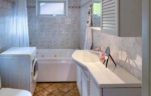 a bathroom with a tub and a sink and a washing machine at 2 Bedroom Cozy Home In Huskvarna in Huskvarna