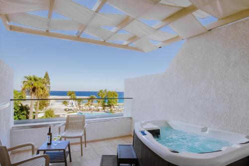 a bath tub on a balcony with a view of the beach at Golden Coast Beach Hotel in Protaras