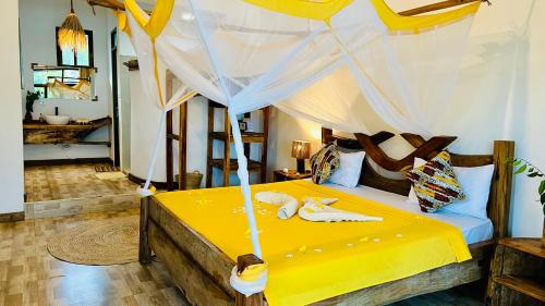 a bedroom with a yellow bed with a canopy at Z-Breeze Zanzibar in Kiwengwa