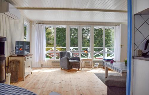 a living room with windows and a couch and a tv at Two-Bedroom Holiday Home In Dronningmolle in Dronningmølle