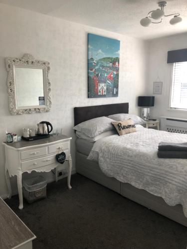a bedroom with a bed and a table and a mirror at Southend Airport Bed & Breakfast in Rochford