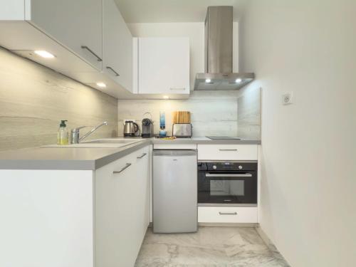 La cuisine blanche est équipée d'un évier et d'un réfrigérateur. dans l'établissement Le Cirrode by Winsome Destination, à Cannes