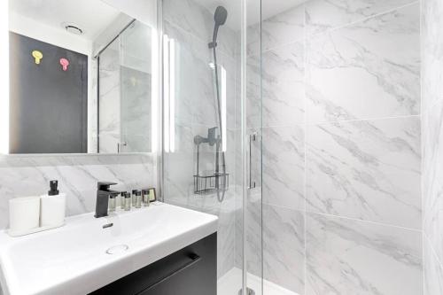une salle de bain blanche avec un lavabo et une douche dans l'établissement Charming Apartment Batignolles 6P, à Paris