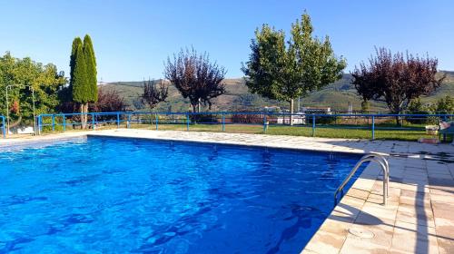 a swimming pool with blue water and trees at Orion Guesthouse Telhado in Fundão