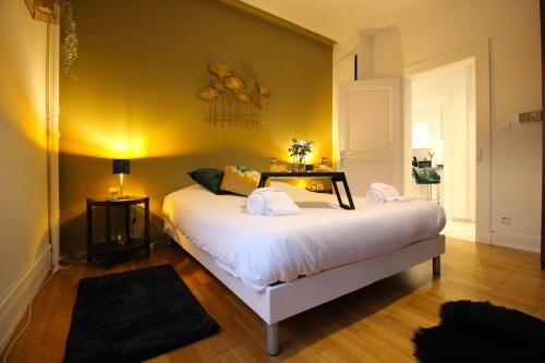 una camera da letto con un grande letto bianco con una parete gialla di Le Shilichic - Gare a Schiltigheim