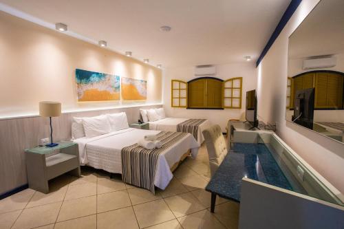 a hotel room with a bed and a tv at Hotel Vilarejo Praia in Rio das Ostras