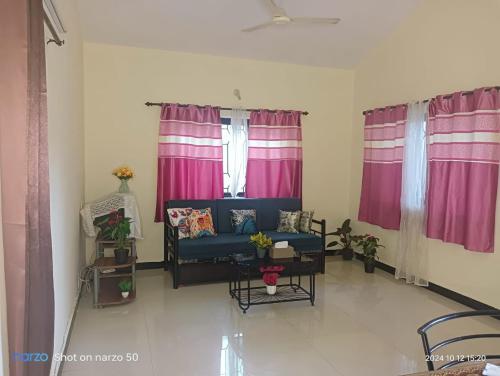 a living room with a blue couch and pink curtains at Lourdina 3bhk Apartment in Candolim