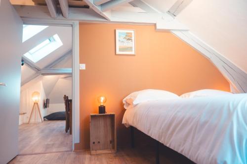 une chambre avec un mur orange avec un lit et une lampe dans l'établissement Le Nid dAigle - Spacieux logement sous les toits, à Tours
