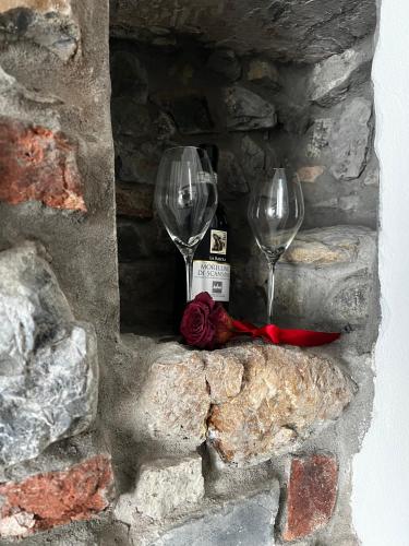 two wine glasses and a bottle in a stone wall at Cascina Ürtigher in Gorno