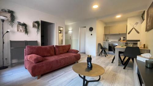 un salon avec un canapé rouge et une cuisine dans l'établissement Appartement confortable 4 personnes à 10 min de strasbourg - Parking inclus, à Schiltigheim
