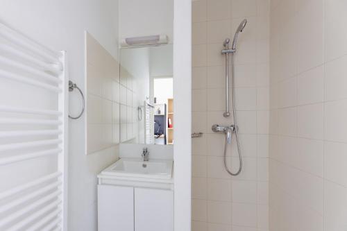 a white bathroom with a shower and a sink at Résidence Kley Marseille République in Marseille