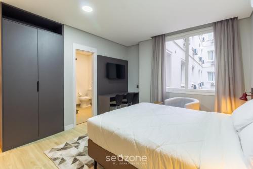 a bedroom with a white bed and a window at TCO - Apartamentos no Centro Histórico Porto Alegre/RS in Porto Alegre
