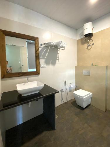 a bathroom with a sink and a toilet and a mirror at Magic Sand Beach Resort in Arambol