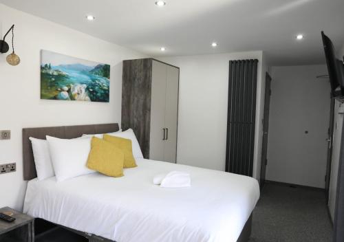 a bedroom with a large white bed with yellow pillows at CB Stays Contractor Hub Peterborough in Peterborough