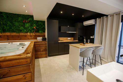 a bathroom with a tub and a kitchen with stools at L'Hakuna - Suite & Spa in Fontaine-Notre-Dame