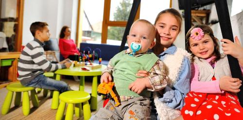three children sitting on a swing with a baby at Penzion Maria in Liptovský Mikuláš