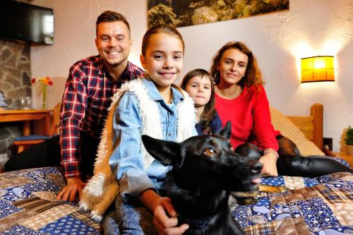 a family sitting on a bed with a dog at Penzion Maria in Liptovský Mikuláš