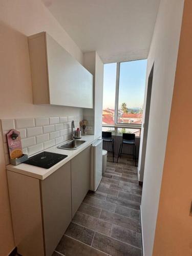 une petite cuisine avec un évier et une fenêtre dans l'établissement La dune vue mer, à La Seyne-sur-Mer