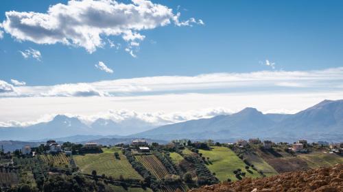 a town on a hill with mountains in the background at Dimora Campo delle Mura - Charming House in Acquaviva Picena