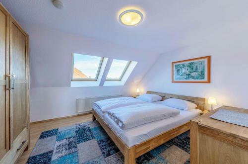 a white bedroom with a bed and two windows at Ferienwohnung Seeblick - Ferienwohnung mit Ausblick auf den Yachthafen in Waren