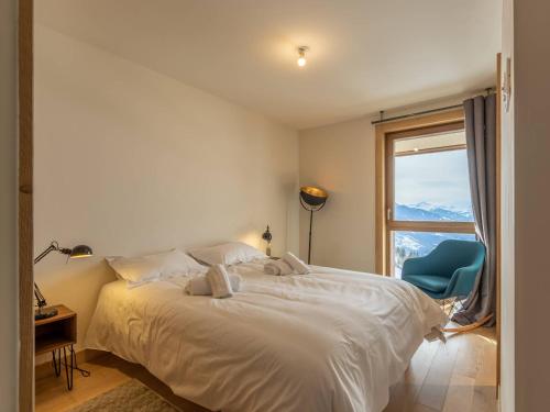 une chambre avec un lit avec une fenêtre et une chaise bleue dans l'établissement Duplex confort avec piscine et spa, pied des pistes - FR-1-461A-5, à Arc 1600