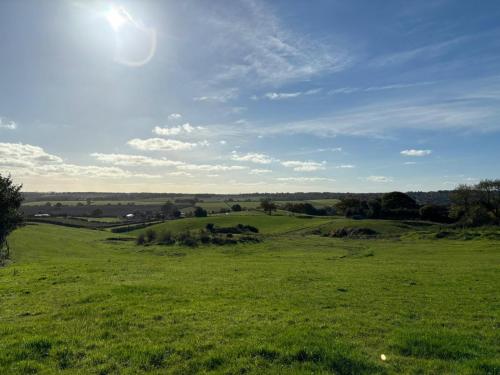 a field of green grass with the sun in the sky at POPPY LUXURY LODGE Sleeps 8 at Fairview Farm, Ravenshead, Nottingham Near Sherwood Forest, Dog Friendly, Farm Stay great for wedding groups, families, Hen Do's, friends gatherings with amazing views in Blidworth