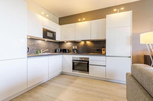 a kitchen with white cabinets and a couch at Dünenquartier - 3 Obergeschoss mit Ostseeblick - 600m zum Strand in Wustrow