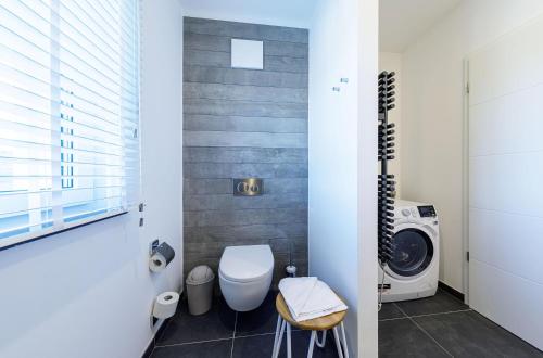 a bathroom with a toilet and a washing machine at Dünenquartier - 3 Obergeschoss mit Ostseeblick - 600m zum Strand in Wustrow
