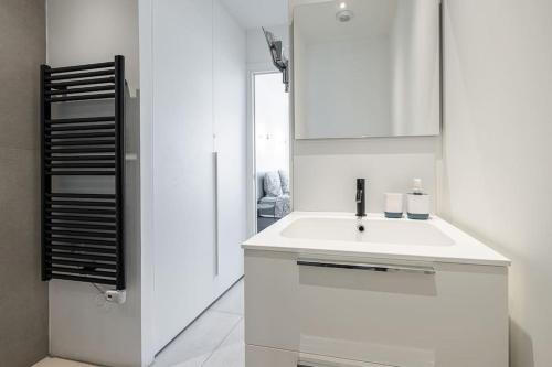 une salle de bain blanche avec un lavabo et un miroir dans l'établissement Royal Riviera, à Nice
