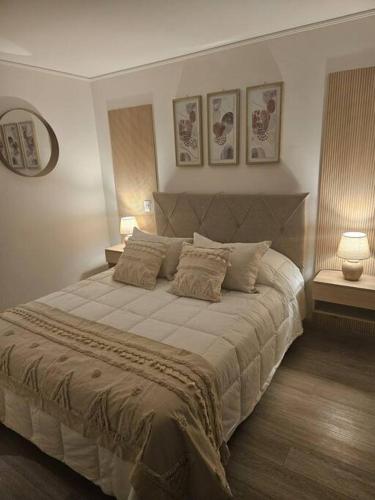 Un dormitorio con una cama grande con dos lámparas. en Depto Mirador del Fiordo, en Puerto Natales